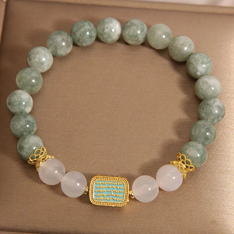 Natural crystal bracelet for women oil green emerald colour with sutra carvings on a white background