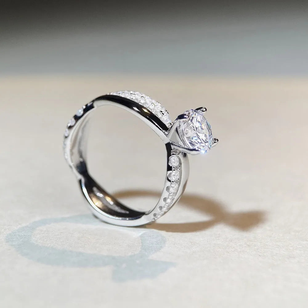 Silver moissanite ring with 1 carat stone, four-claw setting, and geometric cross design on a twisted arm band.