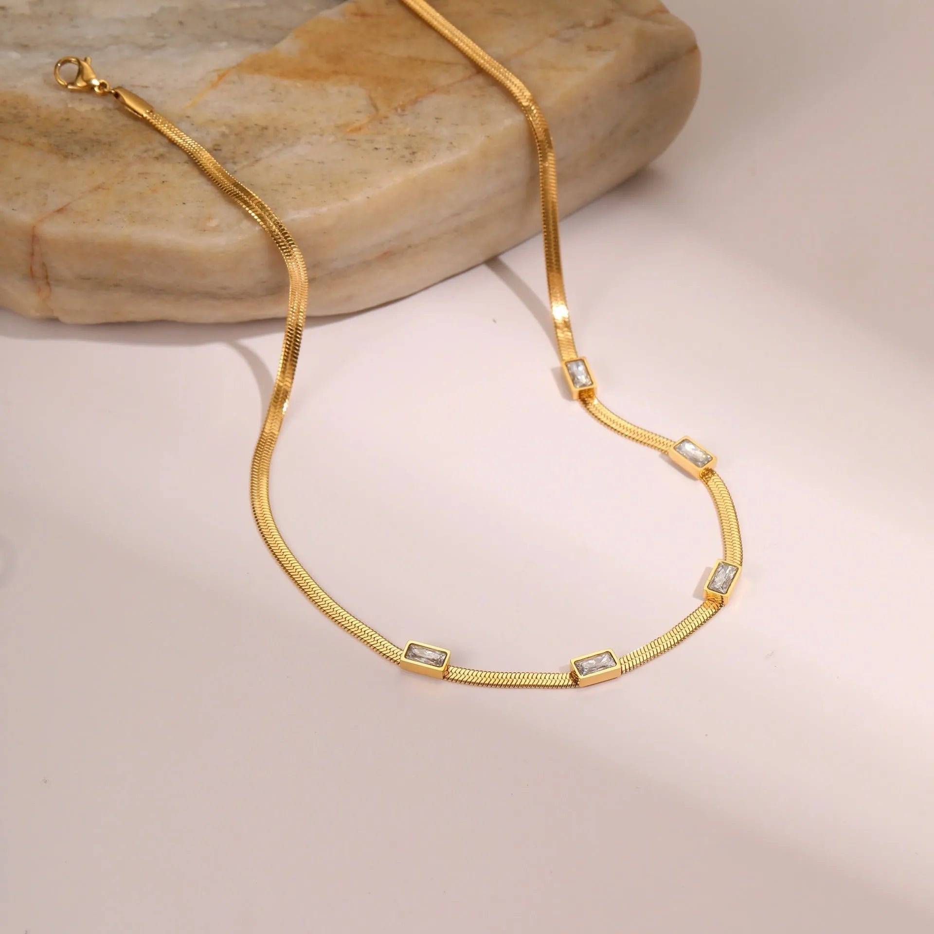 Retro geometric square zircon pendant on a stainless steel flat snake chain necklace in a gold colour finish.
