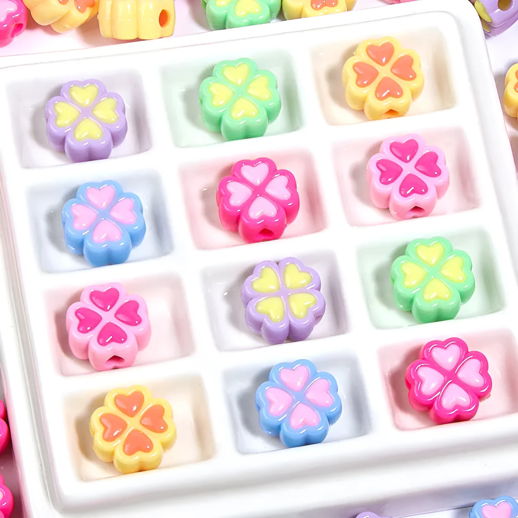 Assortment of 15mm frosted acrylic four-leaf clover craft beads in light colours.