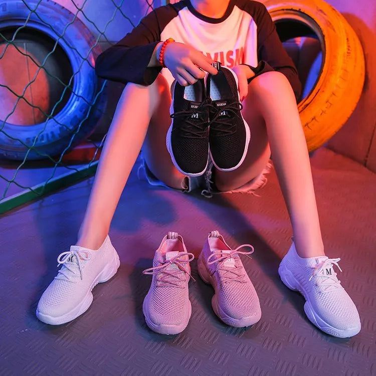 Women's white thick-soled woven trainers with front strap fastening on a plain background.