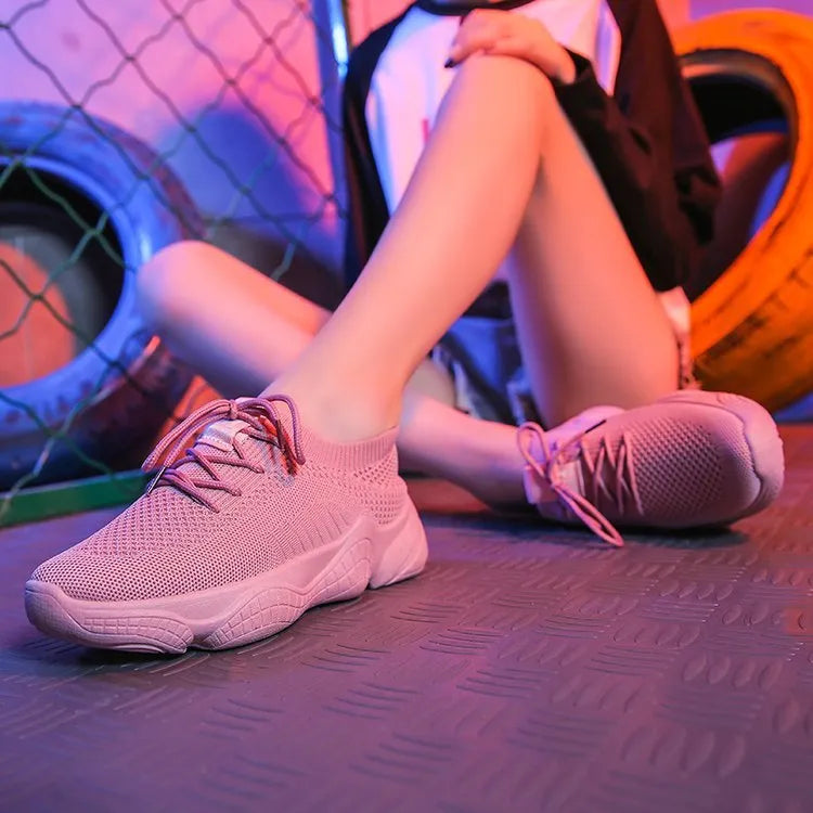 Women's white thick-soled woven trainers with front strap fastening on a plain background.