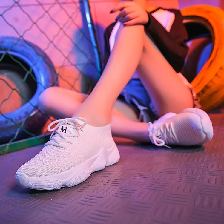 Women's white thick-soled woven trainers with front strap fastening on a plain background.
