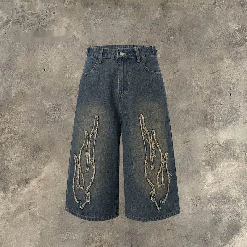 Men's black denim shorts with cropped length and flame embroidery patches on the leg.