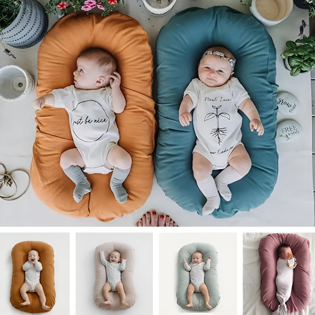Beige portable baby nest cot cushion measuring 75cm by 45cm on a floor.
