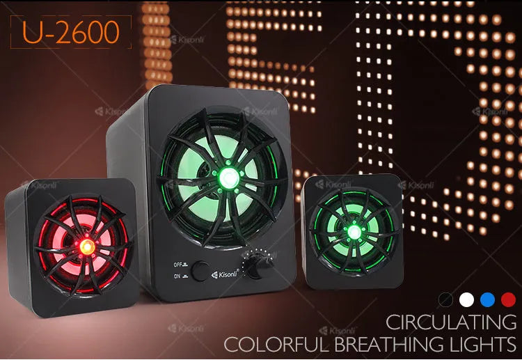 Green 2.1 USB computer speaker with glowing coloured lights on a desk next to a laptop.