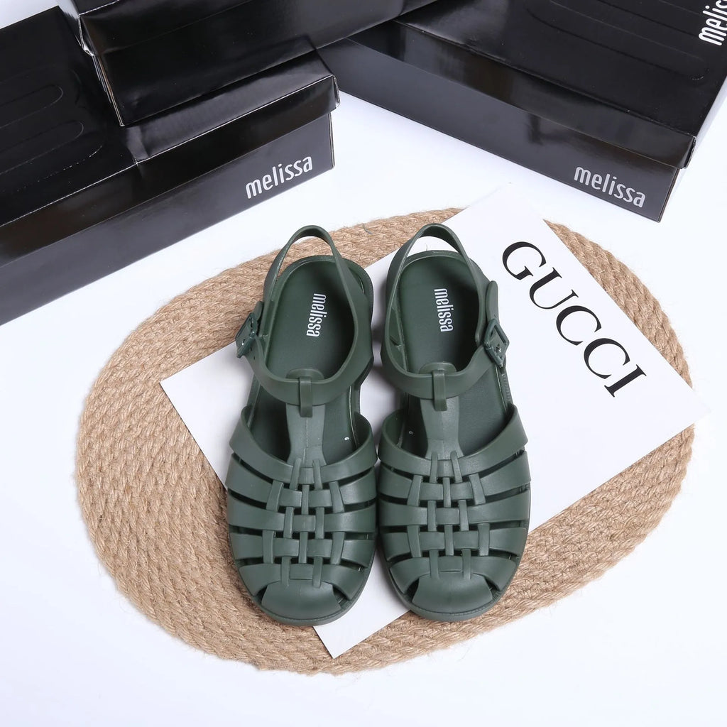 A pair of low-top PVC Roman sandals with a buckle fastening and hollow-out design in matte black.