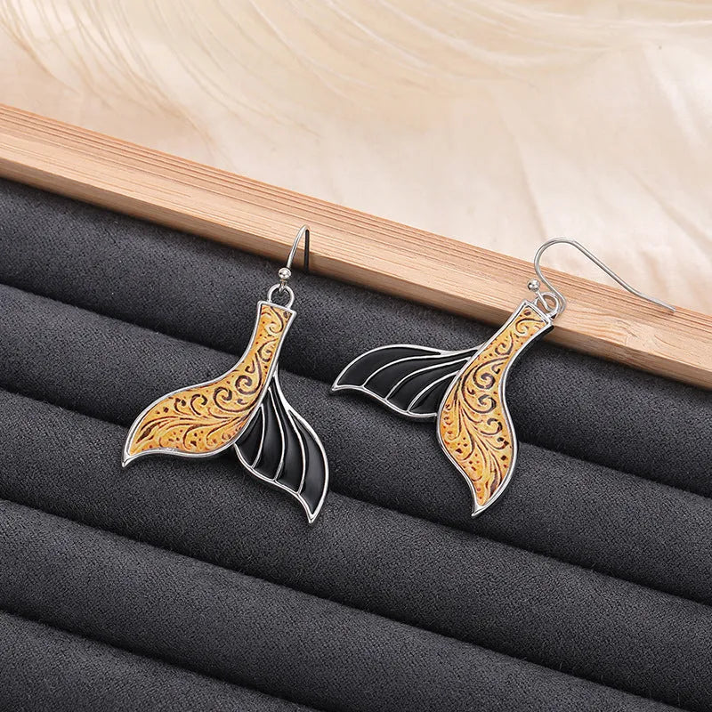 Close-up of women's retro fishtail earrings with a whale design in white gold colour.