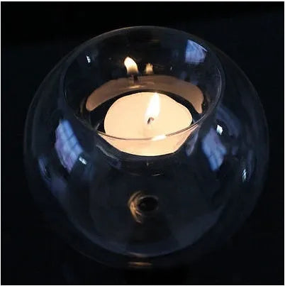 Handmade round hollow glass candle holder in three sizes on a wooden table.