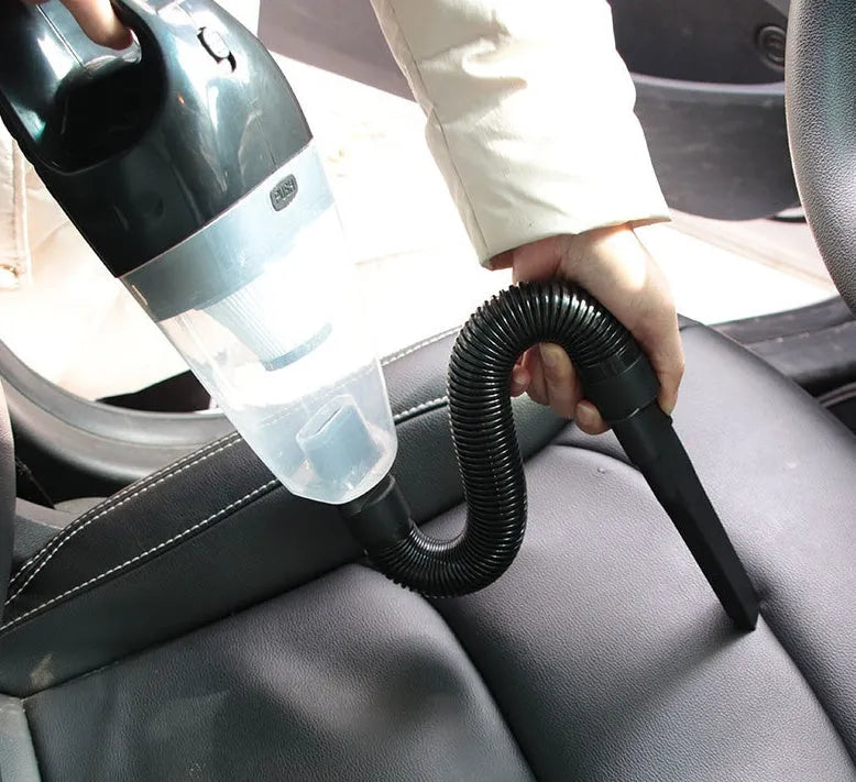 Orange and black 12V portable handheld car vacuum cleaner with nozzles on a car seat.