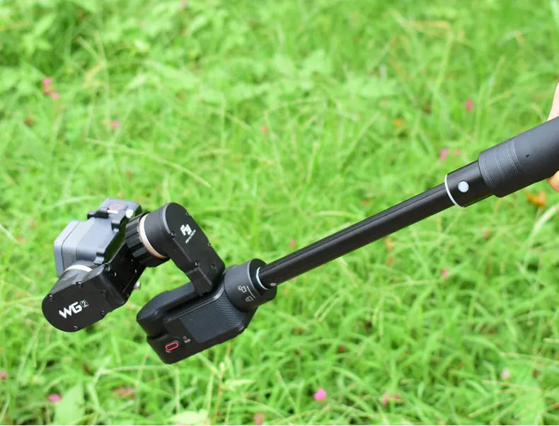 Retracted and extended views of a black aluminium selfie stick with phone holder and separate Bluetooth remote.