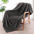 Children's soft polyester plaid blanket in camel colour, folded on a bed