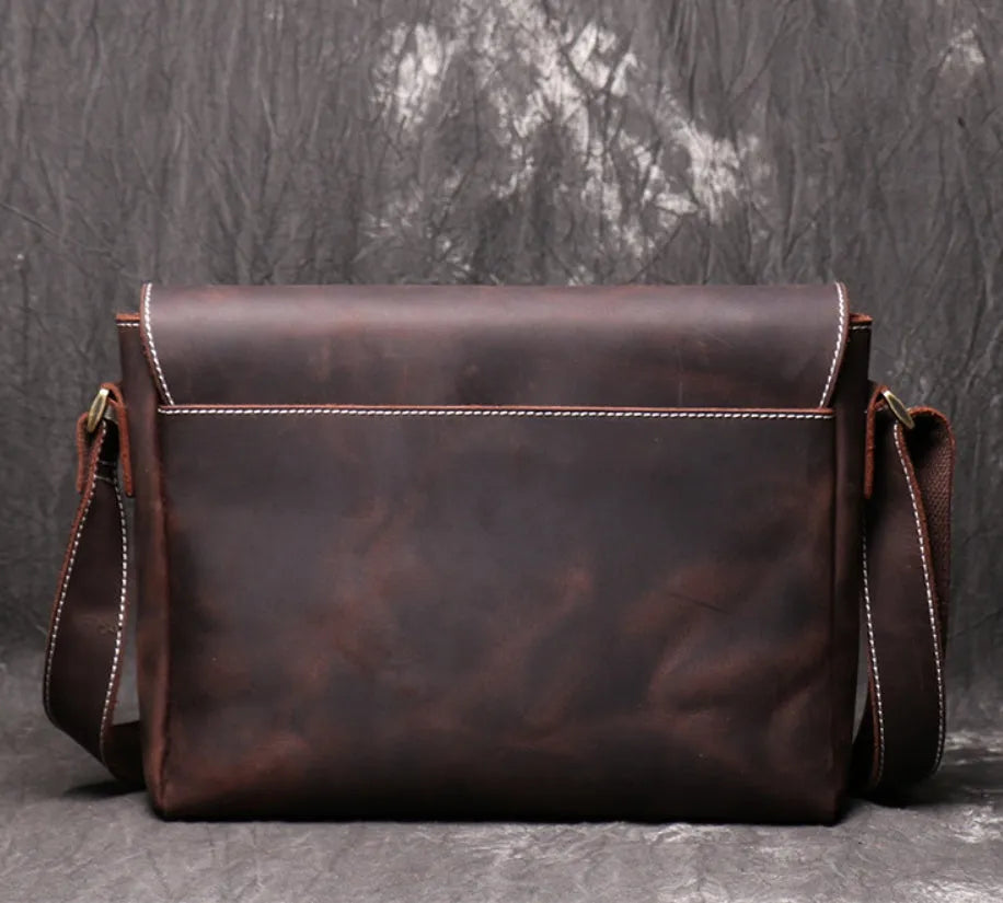 Vintage brown leather mens messenger bag with a shoulder strap, shown open to reveal internal organiser pockets.