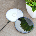 Black 15W Qi wireless charging pad on a wooden surface showing blue LED charging light