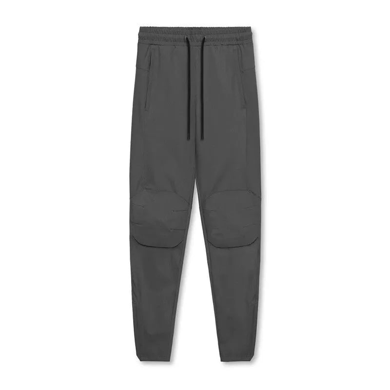 Man wearing dark grey quick-dry fitness trousers with ankle ties, suitable for running and gym workouts.