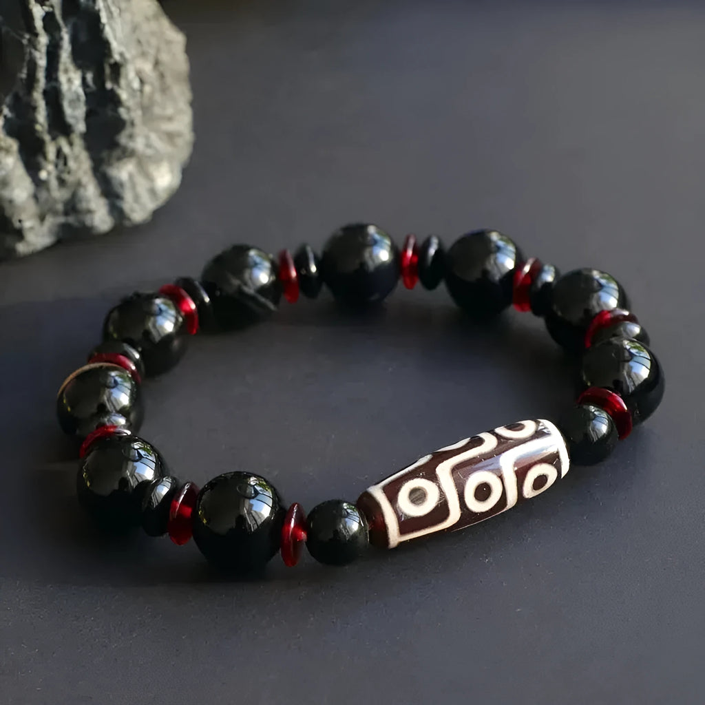 Hand-woven black agate Dzi bead bracelet on a wrist, showing geometric bead and woven band.