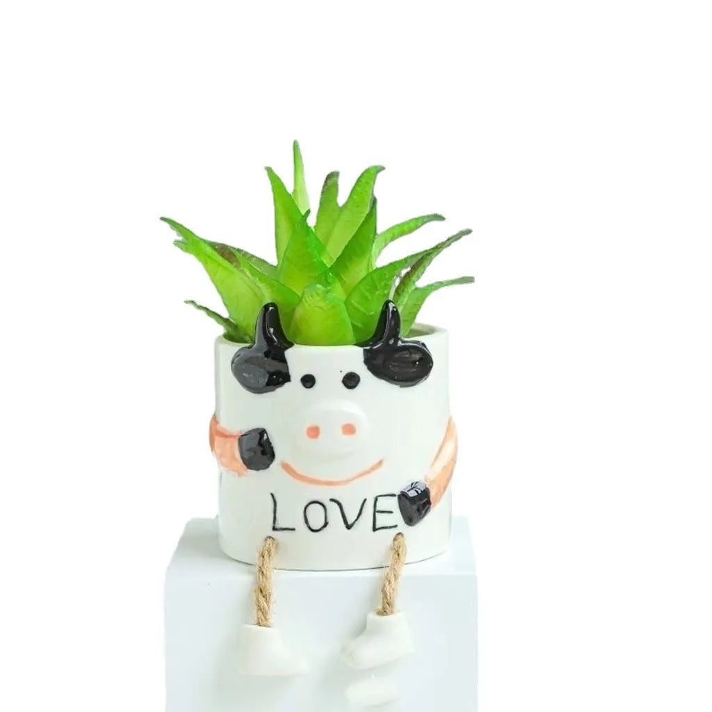 Cartoon style ceramic hanging foot succulent planter on a desktop.