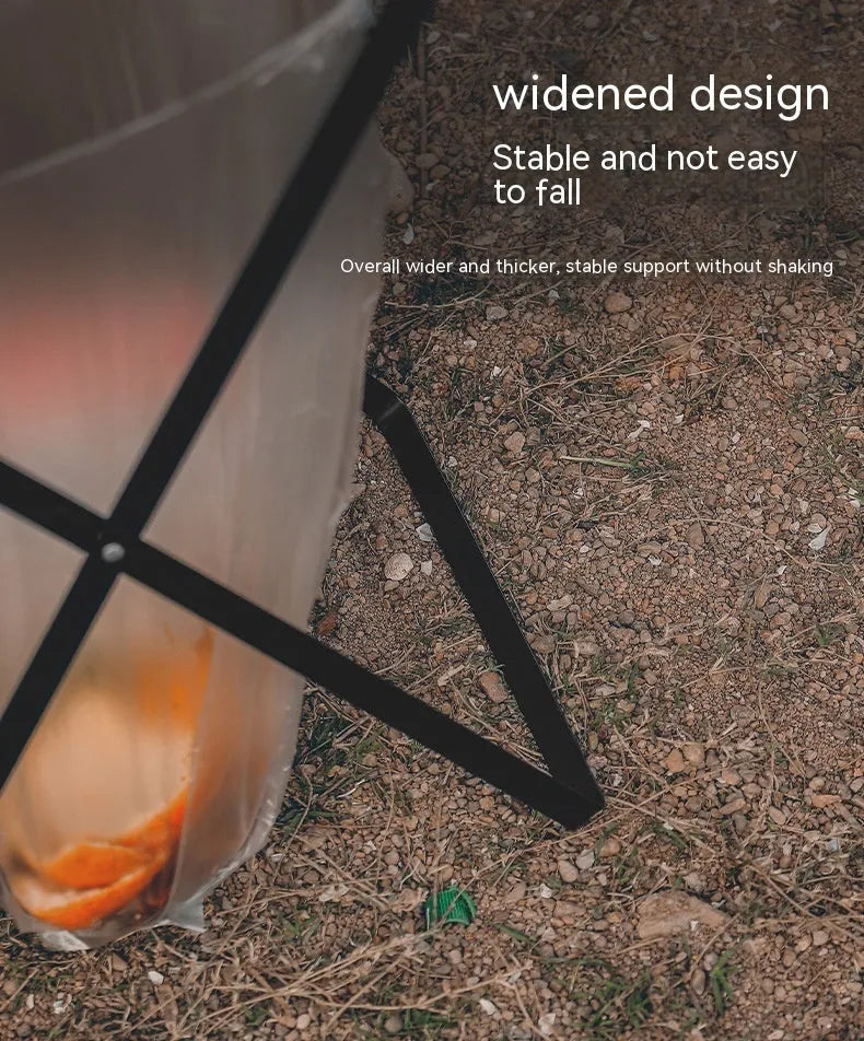 Black folding iron trash rack with a wooden handle holding a rubbish bag outdoors.