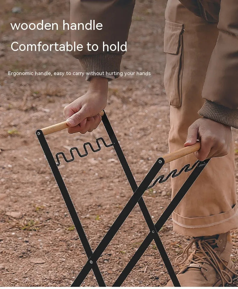 Black folding iron trash rack with a wooden handle holding a rubbish bag outdoors.