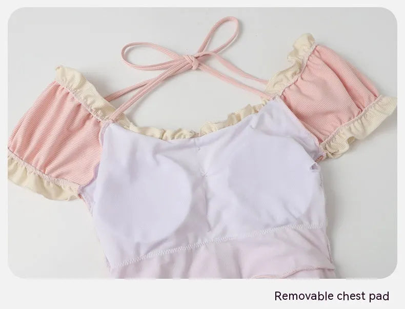 Pink women's conservative one-piece Siamese swimsuit on a hanger.