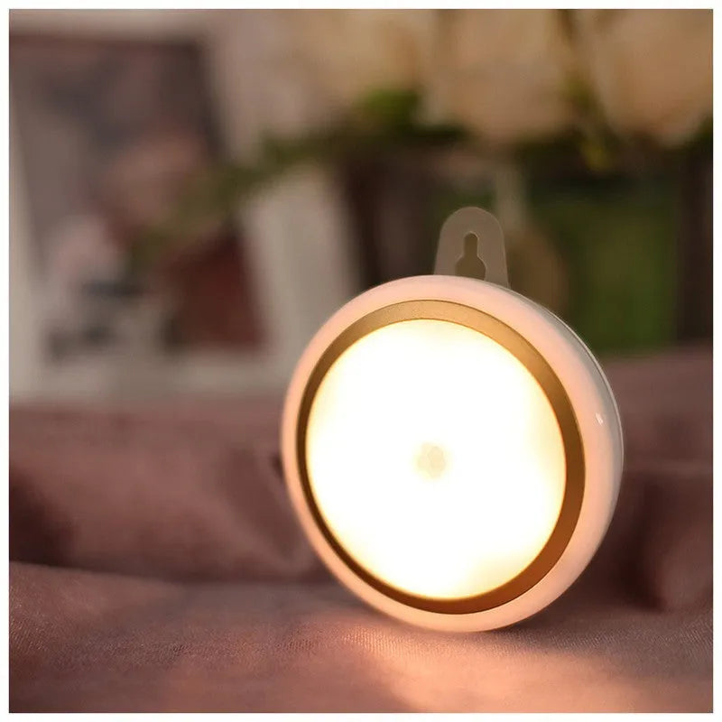 Round white motion sensor LED light unit with battery compartment, 80mm diameter.