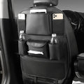Black leather car seat back storage bag with pockets, shown suspended behind a car seat headrest.