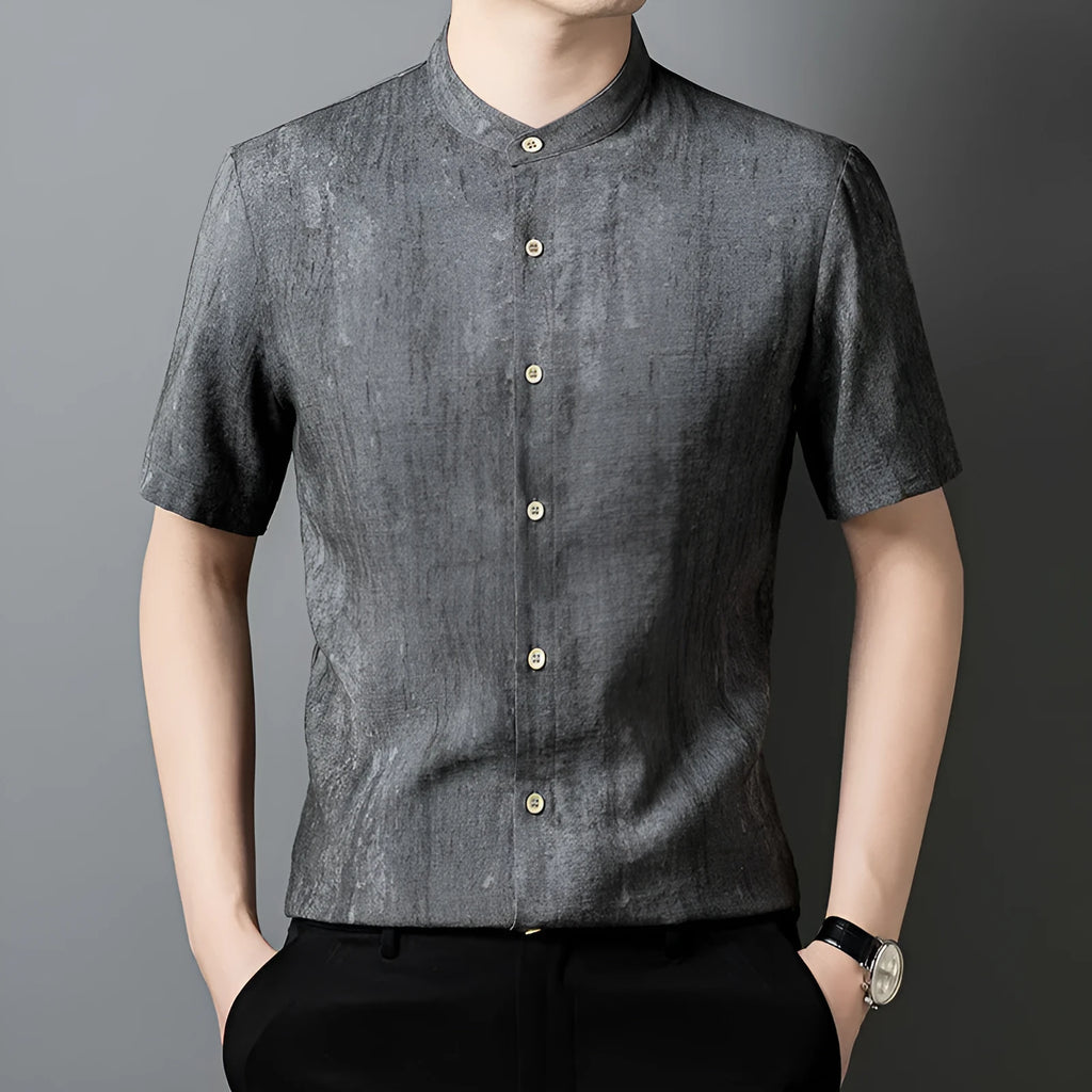 A man wearing a loose-fitting, short-sleeved casual shirt with a stand collar in a grey colour.