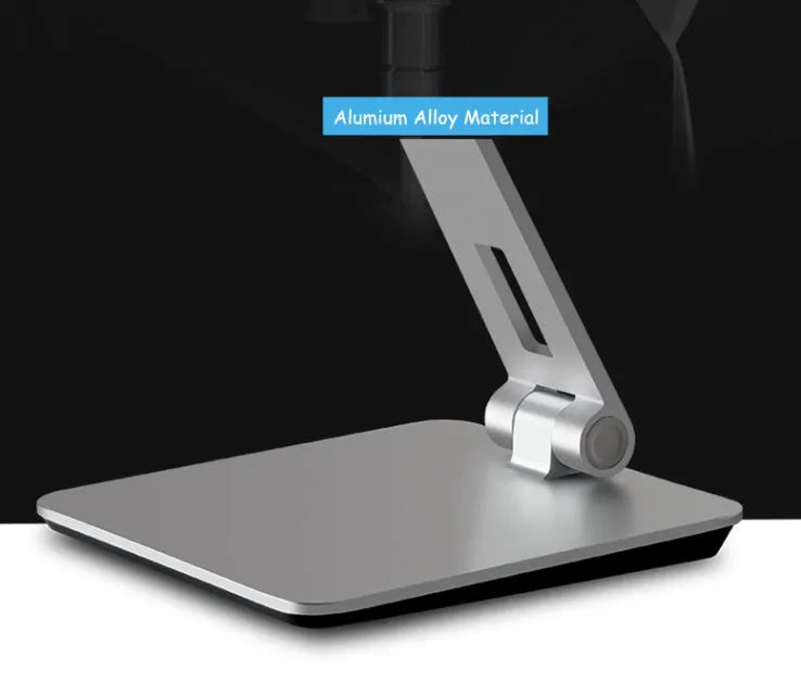 Folding aluminium and black plastic phone tablet stand on a desk, showing 360 degree rotation base.