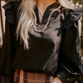 Black women's long sleeve blouse with v-neck ruffle detail and white contrast stitching