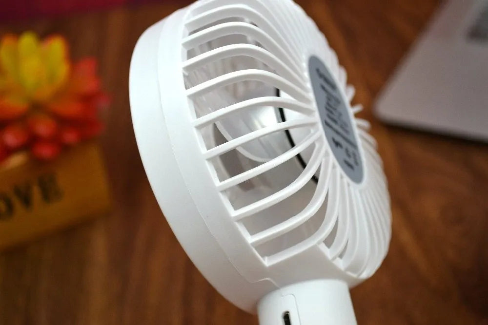 White ORICO FH1 handheld USB rechargeable small fan with three-speed buttons on a desktop.