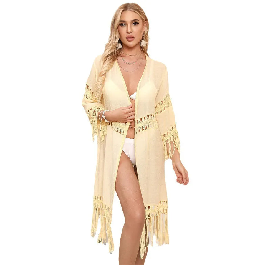 Yellow hand-crocheted beach cardigan with tassel stitching on a hanger.