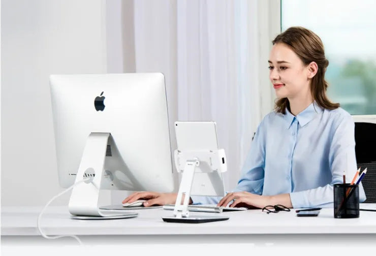 Folding aluminium and black plastic phone tablet stand on a desk, showing 360 degree rotation base.