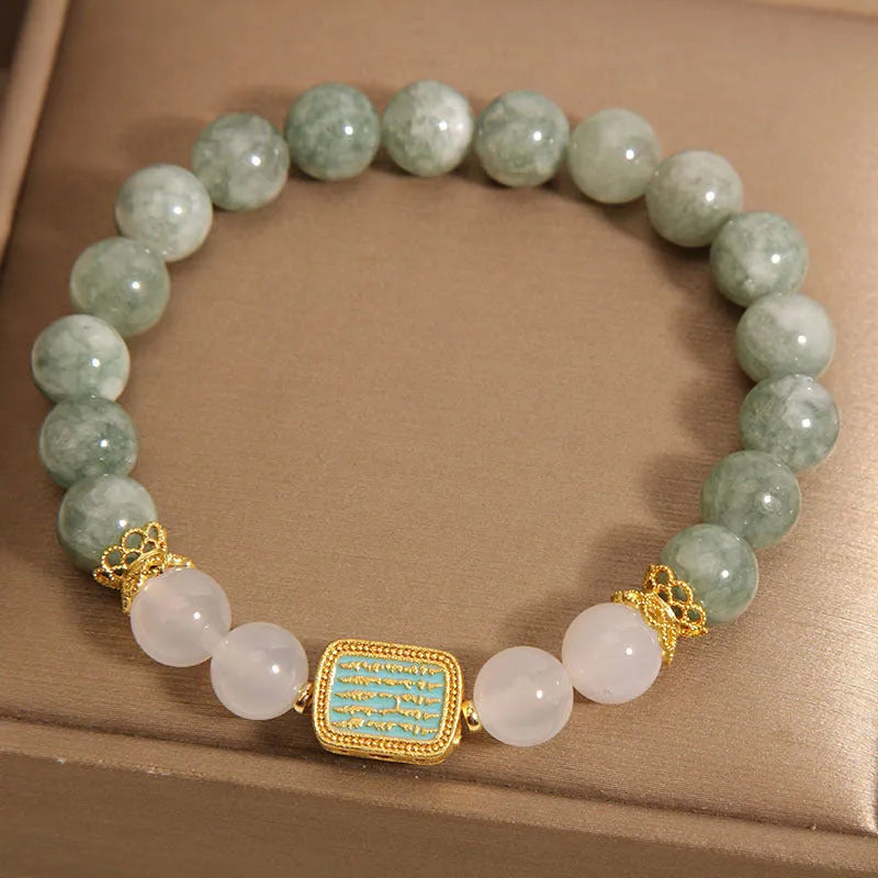 Natural crystal bracelet for women oil green emerald colour with sutra carvings on a white background