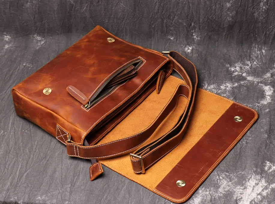 Vintage brown leather mens messenger bag with a shoulder strap, shown open to reveal internal organiser pockets.