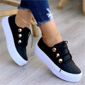 Women's white lace-up flats sneakers with silver rivet detailing on a low round toe.