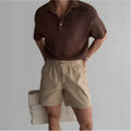 Men's loose-fit cotton sports shorts in black, shown on a hanger against a white background.