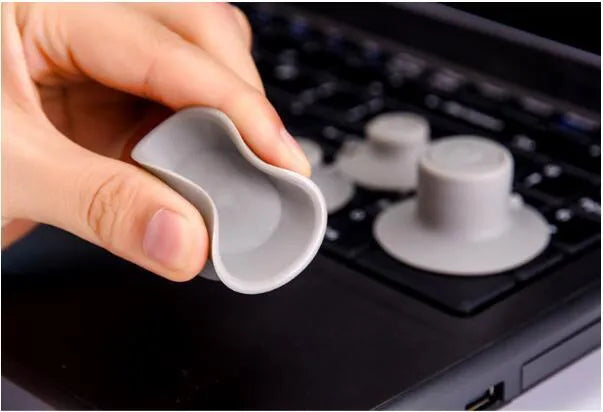 Grey durable plastic laptop cooling pads, two large and two small, on a desk next to a notebook