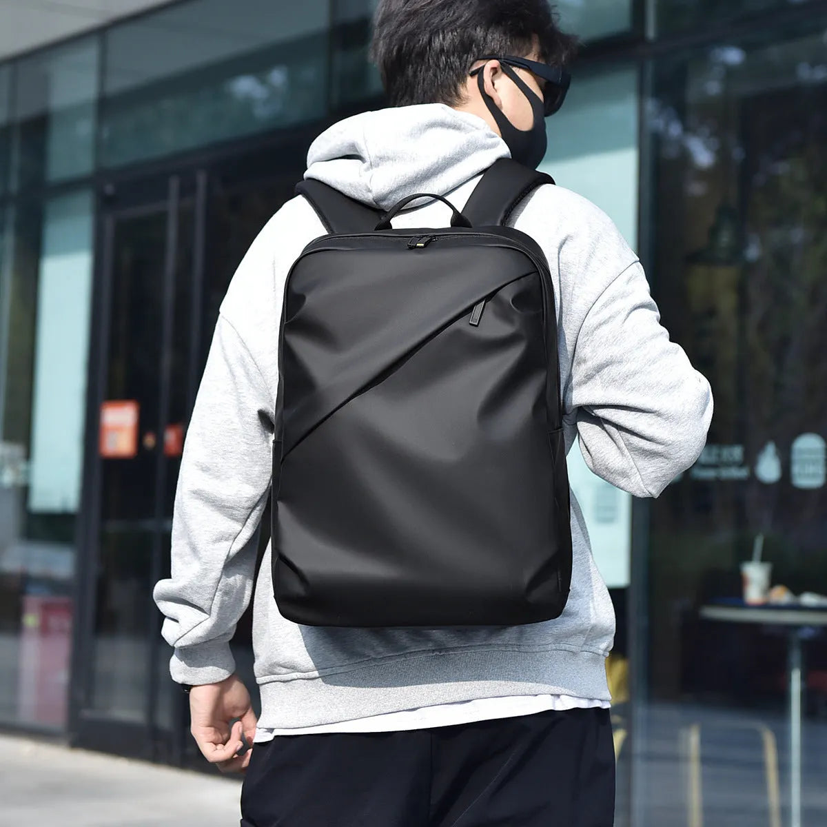 Large simple design waterproof backpack in grey with visible stitching, shown with a separate computer bag.