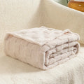 Thickened polyester blanket with geometric pattern in creamy white on a sofa