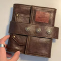 Brown A7 notebook with leather-style buckle closure showing loose-leaf binding