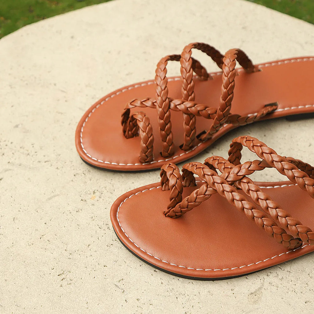 Women's black clip-toe woven flat sandals with rubber sole on a plain background.