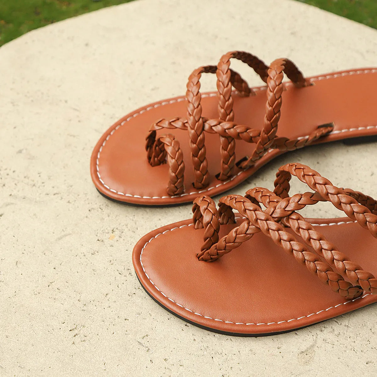 Women's black clip-toe woven flat sandals with rubber sole on a plain background.