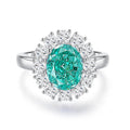 Women's oval emerald and diamond ring in sterling silver on a hand.