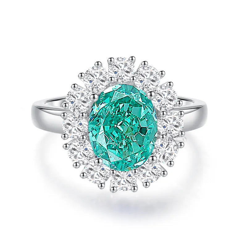 Women's oval emerald and diamond ring in sterling silver on a hand.