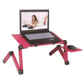 Black folding metal computer desk with laptop and cooling fan, extended on a sofa