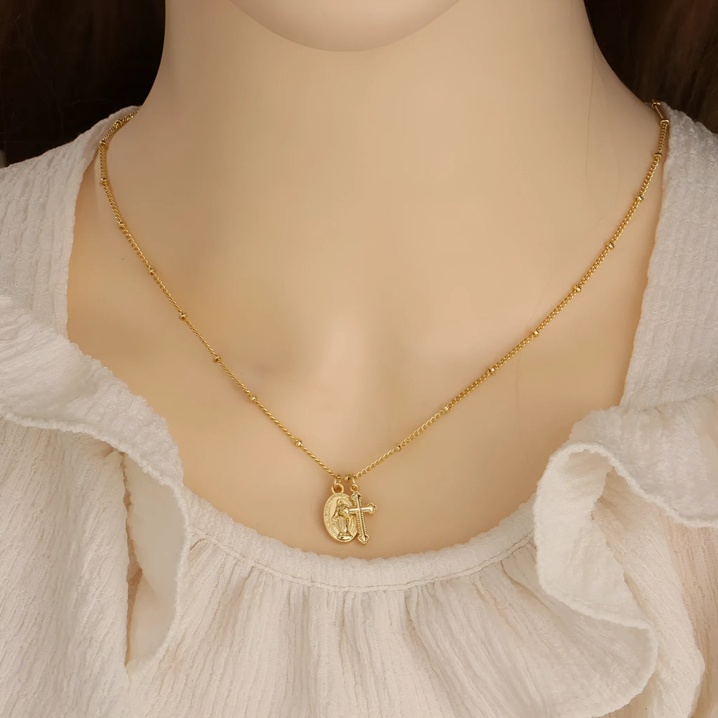 Gold-coloured Virgin Mary and cross pendant necklace on a chain.