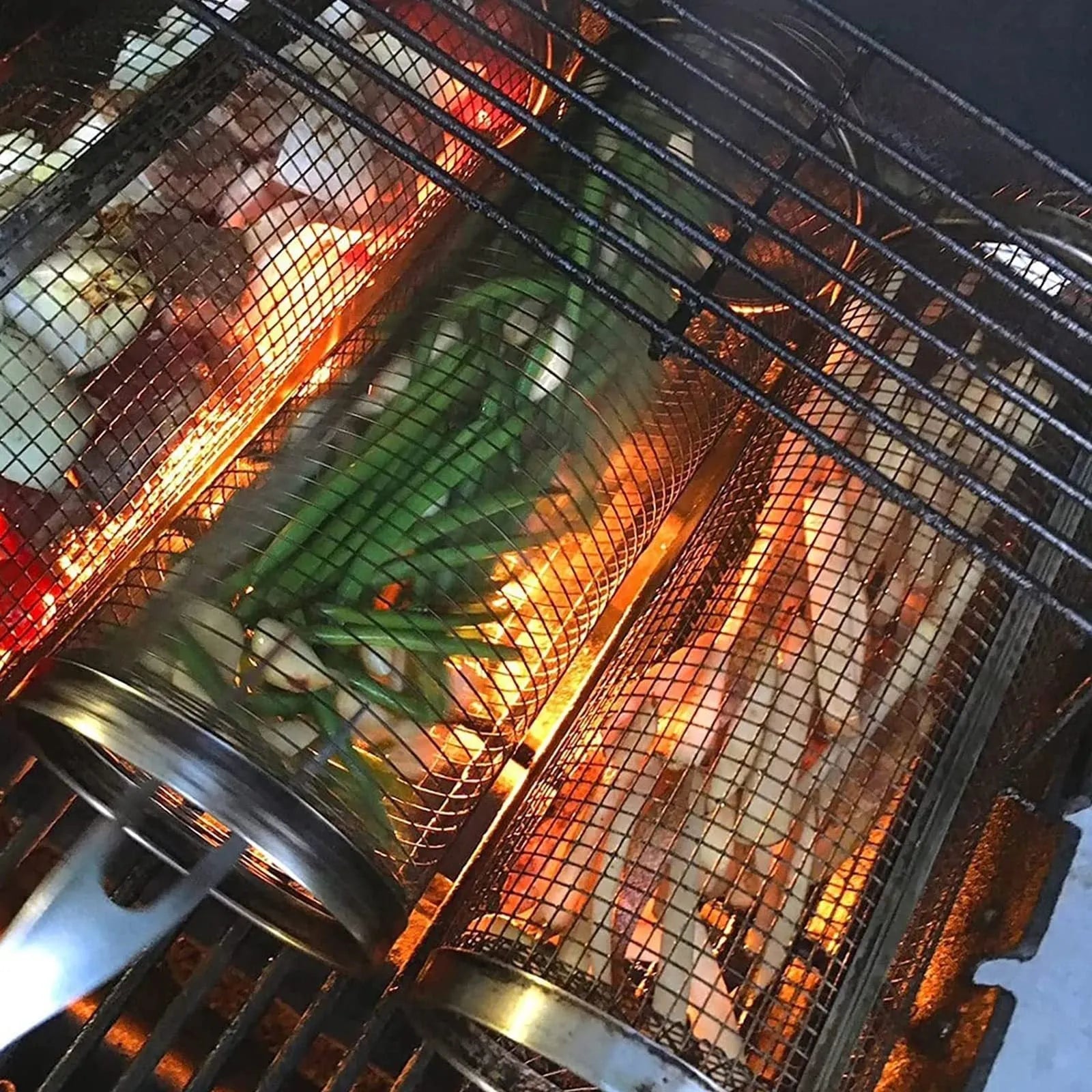 Rolling grill basket metal mesh cylinder with hooks on barbecue, containing vegetables and meat