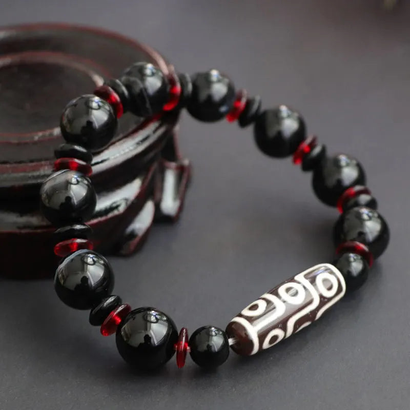 Hand-woven black agate Dzi bead bracelet on a wrist, showing geometric bead and woven band.