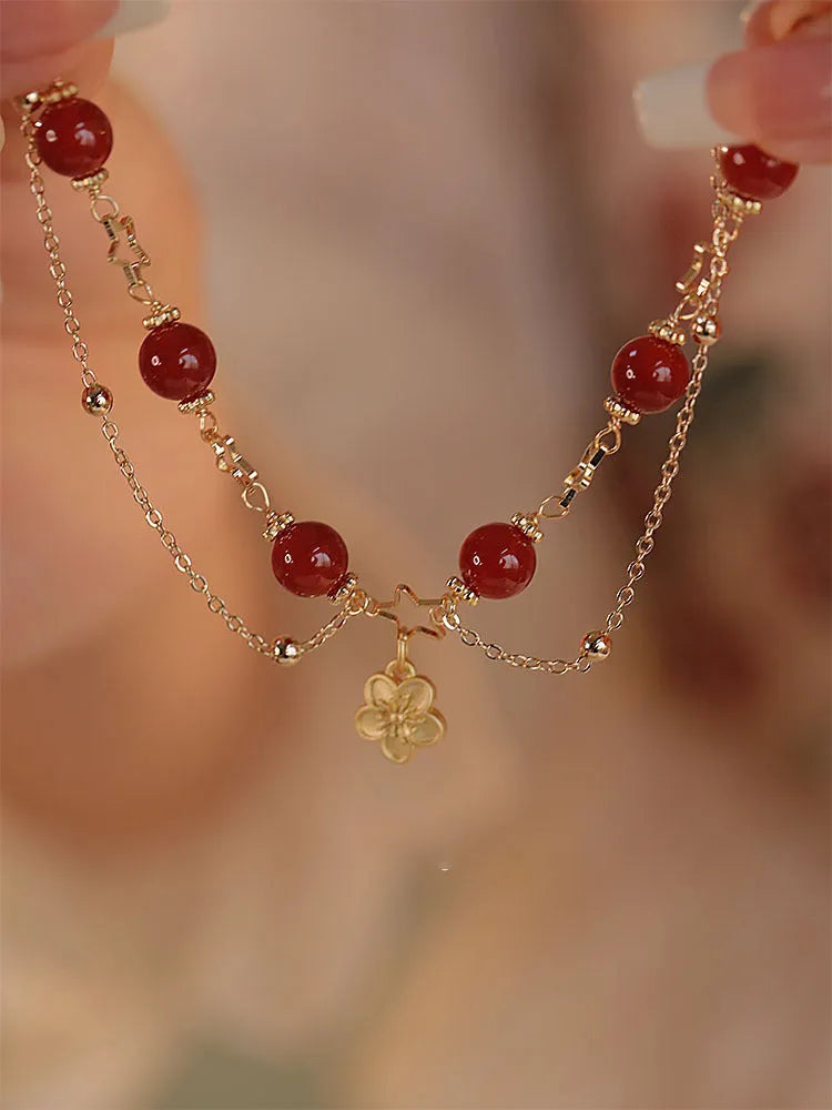 Red agate double layer bracelet with peach blossom charm on an adjustable elastic cord.