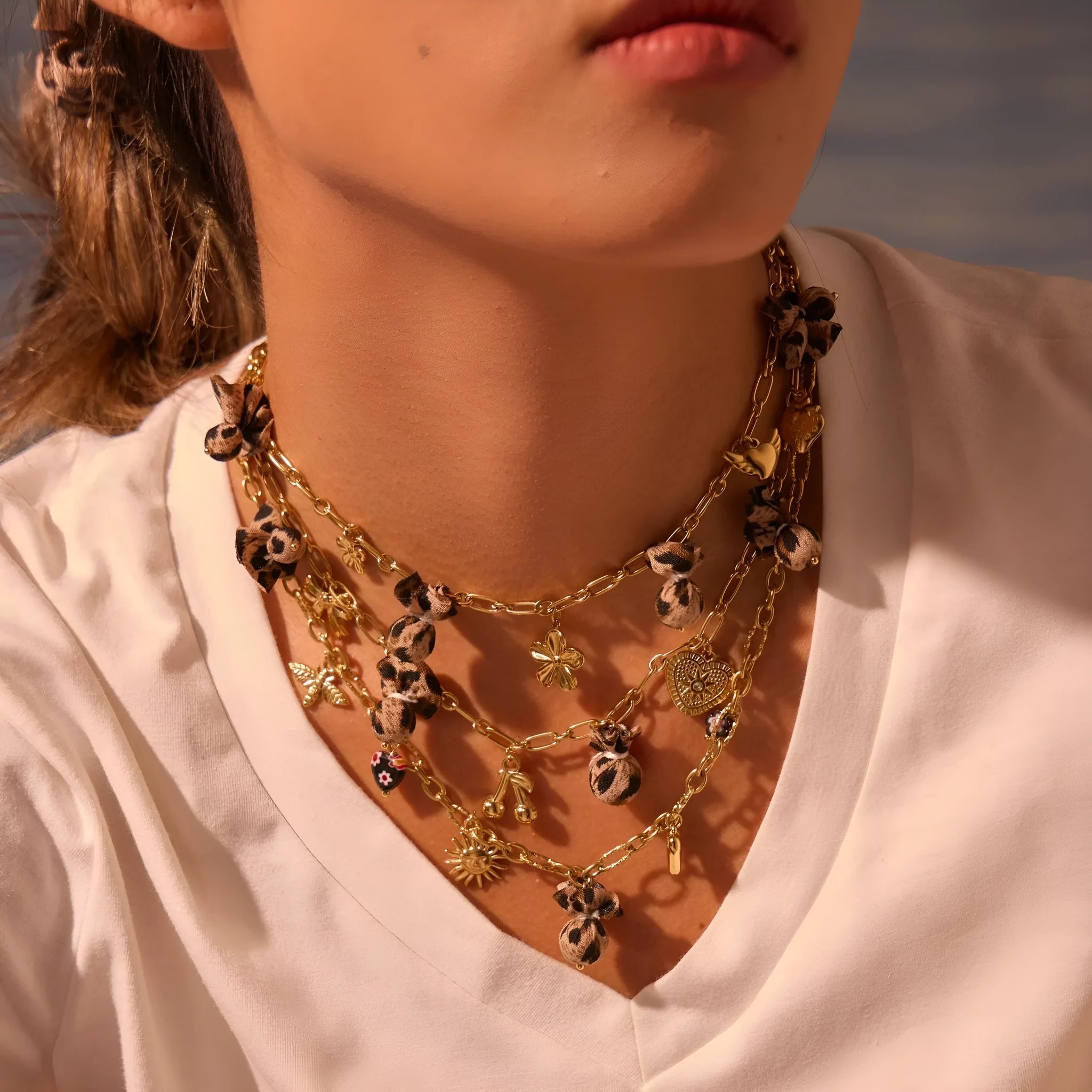 Stainless steel necklace with geometric pendant showing leopard spots, love hearts and flowers in gold finish